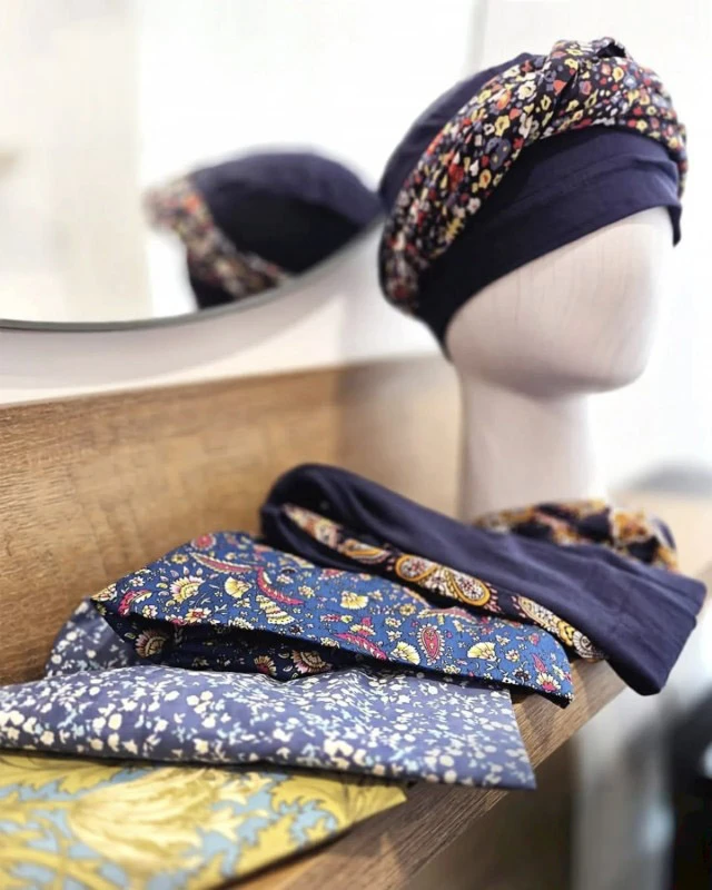 Atelier de confection textile avec mannequin présentant des turbans et bandeaux en tissus à motifs floraux colorés