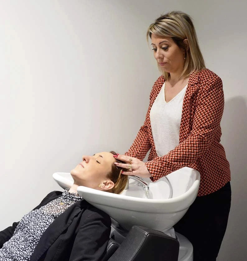 Une femme présente une comparaison capillaire avant/après avec sa main positionnée sur le cuir chevelu