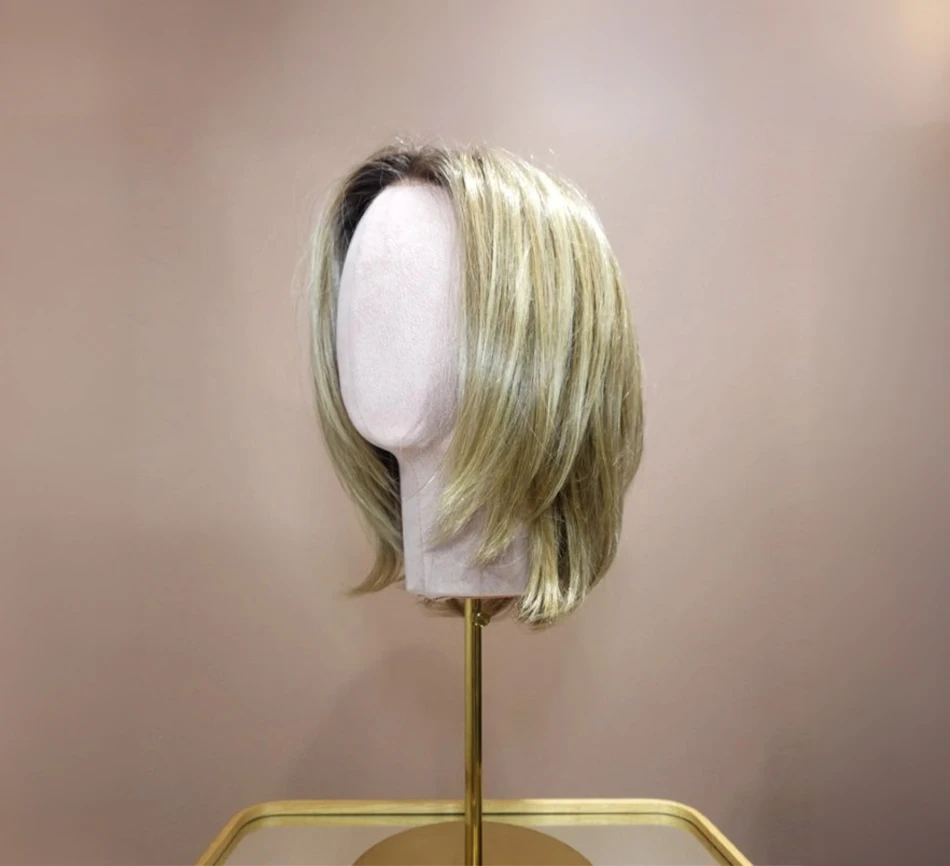 Intérieur moderne avec mannequin tête sur support doré présentant perruque courte blonde aux mèches dégradées