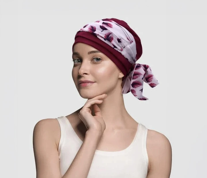 Portrait studio d'une femme élégante portant un turban coloré rouge et doré, bijoux assortis avec collier de perles rouges et noires, boucles d'oreilles rouges