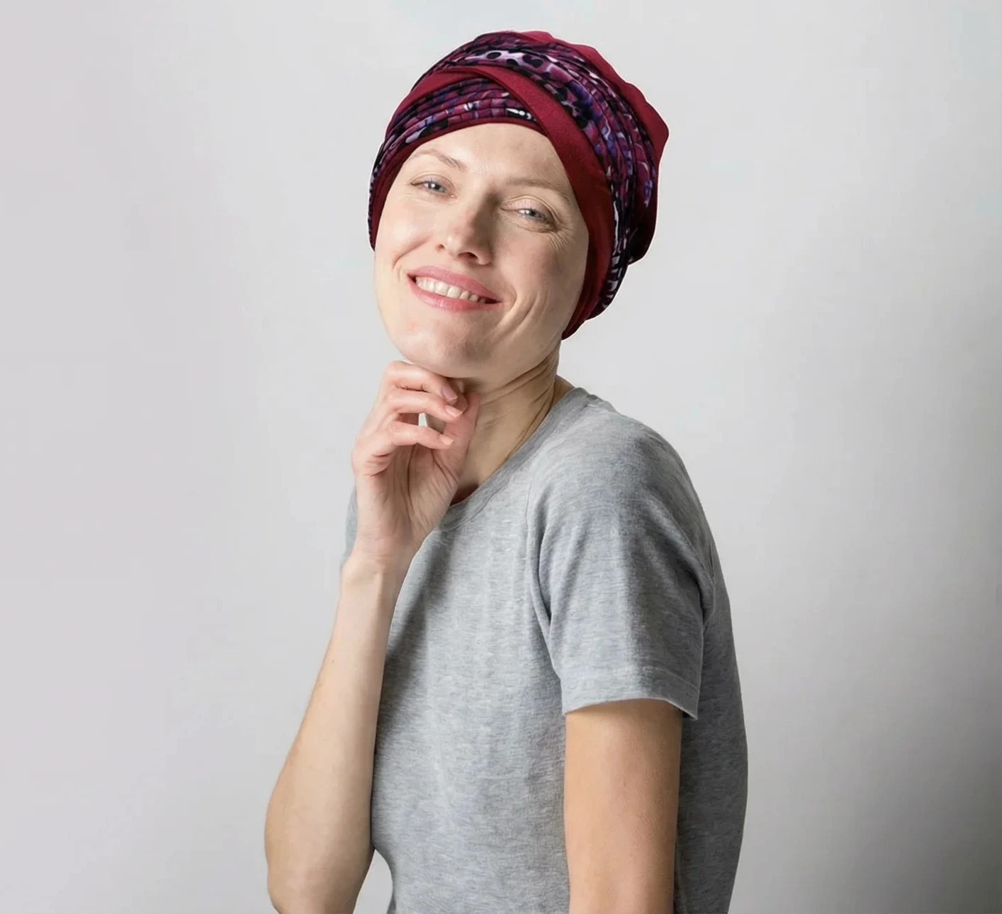 Jeune femme souriante aux cheveux bouclés châtains, épaules nues, regardant par-dessus son épaule dans un studio photo