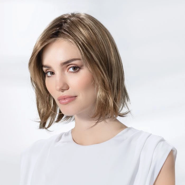 Femme souriante en intérieur sur fond blanc neutre, regard confiant et professionnel