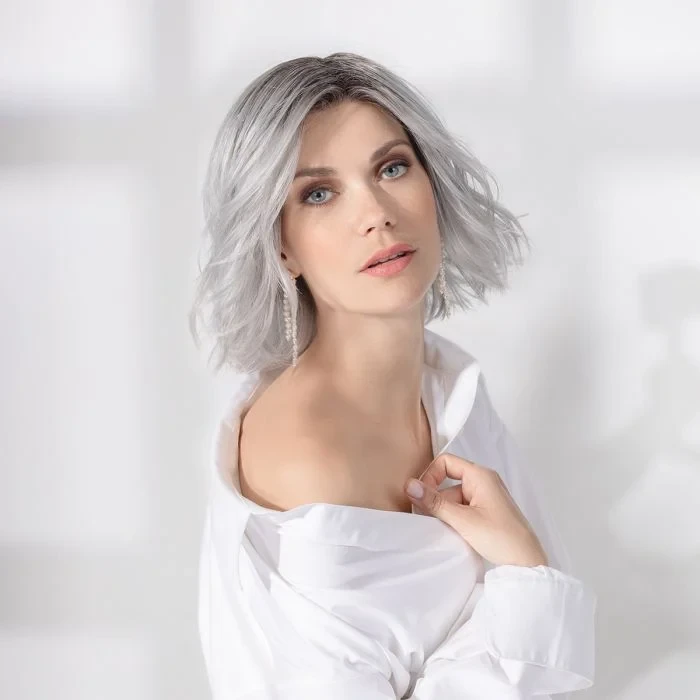 Femme souriante en intérieur sur fond blanc neutre, regard confiant et professionnel
