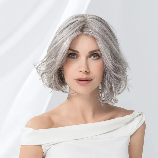 Femme souriante en intérieur sur fond blanc neutre, regard confiant et professionnel