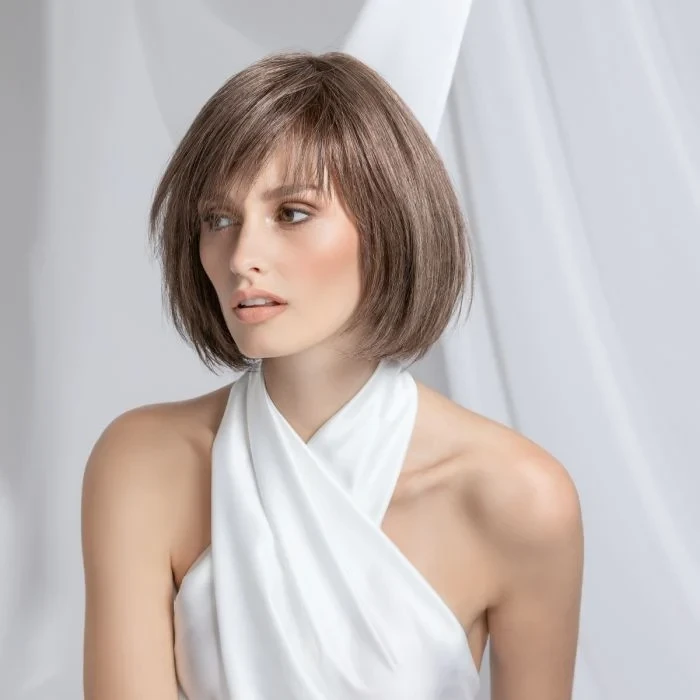Femme souriante en intérieur sur fond blanc neutre, regard confiant et professionnel