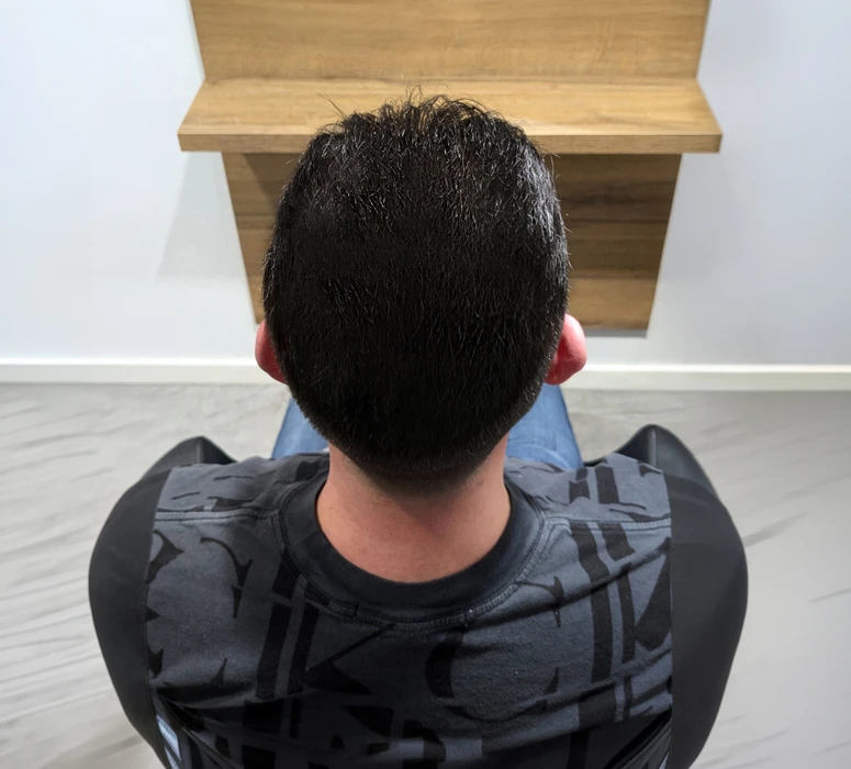 Intérieur de salon de coiffure avec cliente assise dos tourné, cheveux blonds mi-longs aux boucles voluptueuses fraîchement coiffées